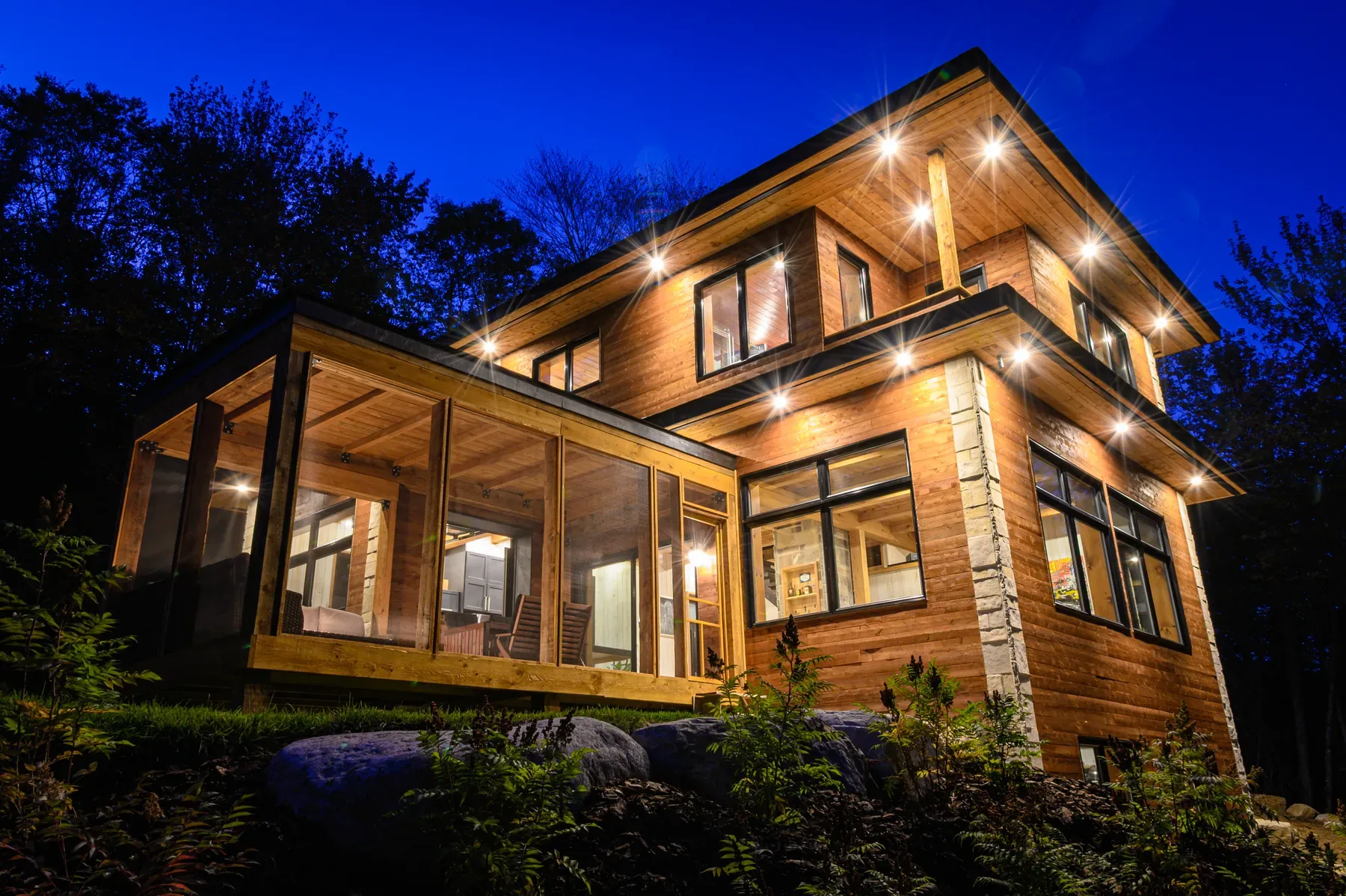 Home built by Canopée Développement, lit up at dusk